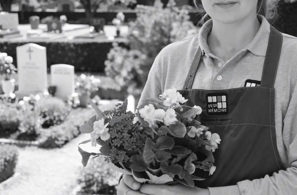 Un professionnel en tablier En sa mémoire dépose des fleurs dans un cimetière français.