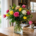 Bouquet coloré de fleurs coupées dans un vase en verre sur une table en bois, intérieur lumineux. conservation fleurs coupées, bouquet frais et fleurissement domestique.