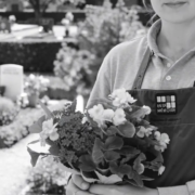 Personne tenant un bouquet de fleurs au cimetière, prêt à fleurir une tombe à distance.