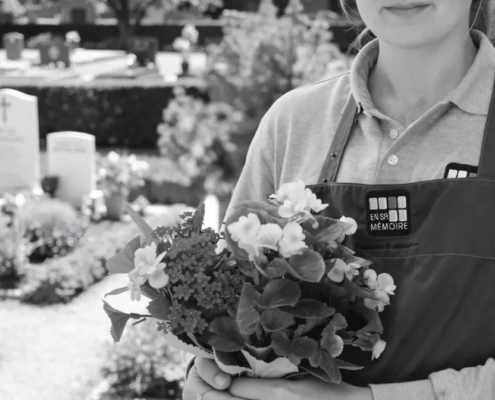 Personne tenant un bouquet de fleurs au cimetière, prêt à fleurir une tombe à distance.