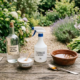 Vinaigre blanc et gros sel pour désherber, accompagné d’un spray pulvé et bol en bois sur une table en bois extérieure.