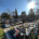 Vue d’un cimetière avec de nombreuses tombes alignées, fleurs et monuments funéraires sous un ciel clair.