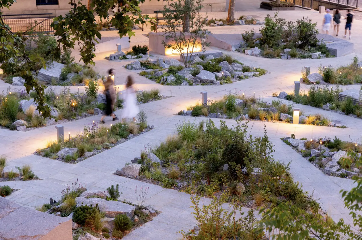 Allée fleurie et paysagée dans un cimetière, éclairages discret sous les lampes, personnes promènent près des sépultures. Des plantations saisonnières et arbustes décorent les chemins. Allée fleurie et paysagée dans un cimetière, éclairages discret sous les lampes, personnes promènent près des sépultures. Des plantations saisonnières et arbustes décorent les chemins.
