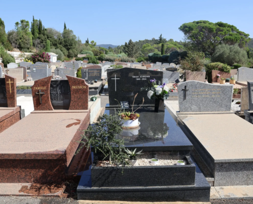 Allée de tombes gravées et tombes en pierrePolitiques de service funéraire avec fleurs fraîches et décorations sur les monuments funéraires dans un cimetière ensoleillé. Mot-clé intégré: entretien tombe (mentionné comme activité liée).