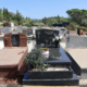 Allée de tombes gravées et tombes en pierrePolitiques de service funéraire avec fleurs fraîches et décorations sur les monuments funéraires dans un cimetière ensoleillé. Mot-clé intégré: entretien tombe (mentionné comme activité liée).