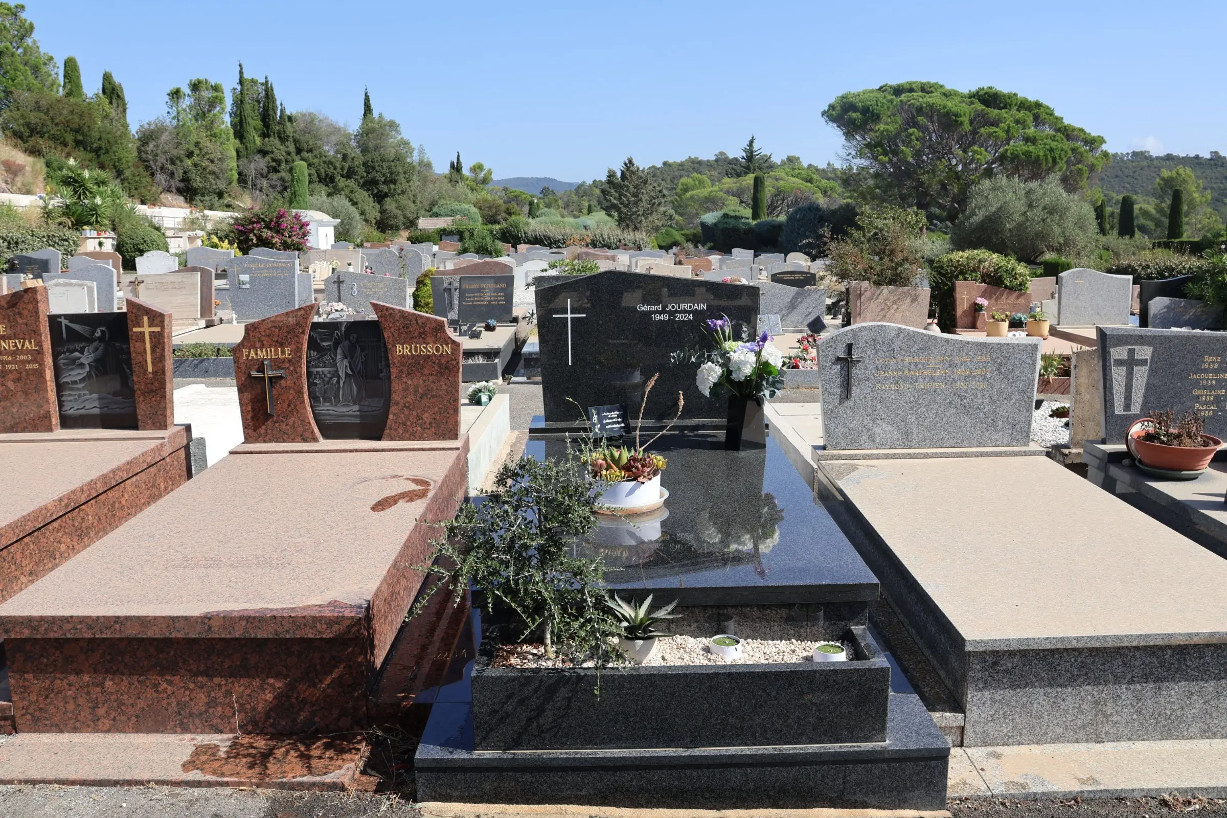 Allée de tombes gravées et tombes en pierrePolitiques de service funéraire avec fleurs fraîches et décorations sur les monuments funéraires dans un cimetière ensoleillé. Mot-clé intégré: entretien tombe (mentionné comme activité liée).