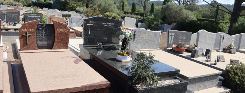 Allées et tombes en pierre dans un cimetière, avec des monuments variés et une végétation en arrière-plan. Altération possible par stations de pierre sombre et gravures, thème de pierre tombale entretien conseils.