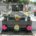Tombe en pierre noire avec motifs gravés et plaques dorées, entourée de vases et bouquets colorés sur le devant. nettoyage de tombe tarif intégré.
