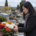 Une femme ajuste un bouquet de fleurs multicolores devant une tombe dans un cimetière.