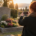 Personne prenant une photo avec son téléphone devant une tombe fleurie au cimetière lors d’un coucher de soleil.