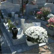 Tombe cremée décorée avec des fleurs et des objets funéraires en pierre et en céramique.