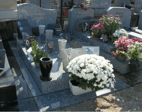 Tombe cremée décorée avec des fleurs et des objets funéraires en pierre et en céramique.