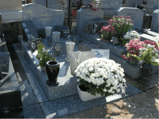 Tombe cremée décorée avec des fleurs et des objets funéraires en pierre et en céramique.