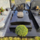 Tombe élégante en granit noir brillant avec un bouquet sphérique de fleurs jaunes au premier plan et plaques gravées,